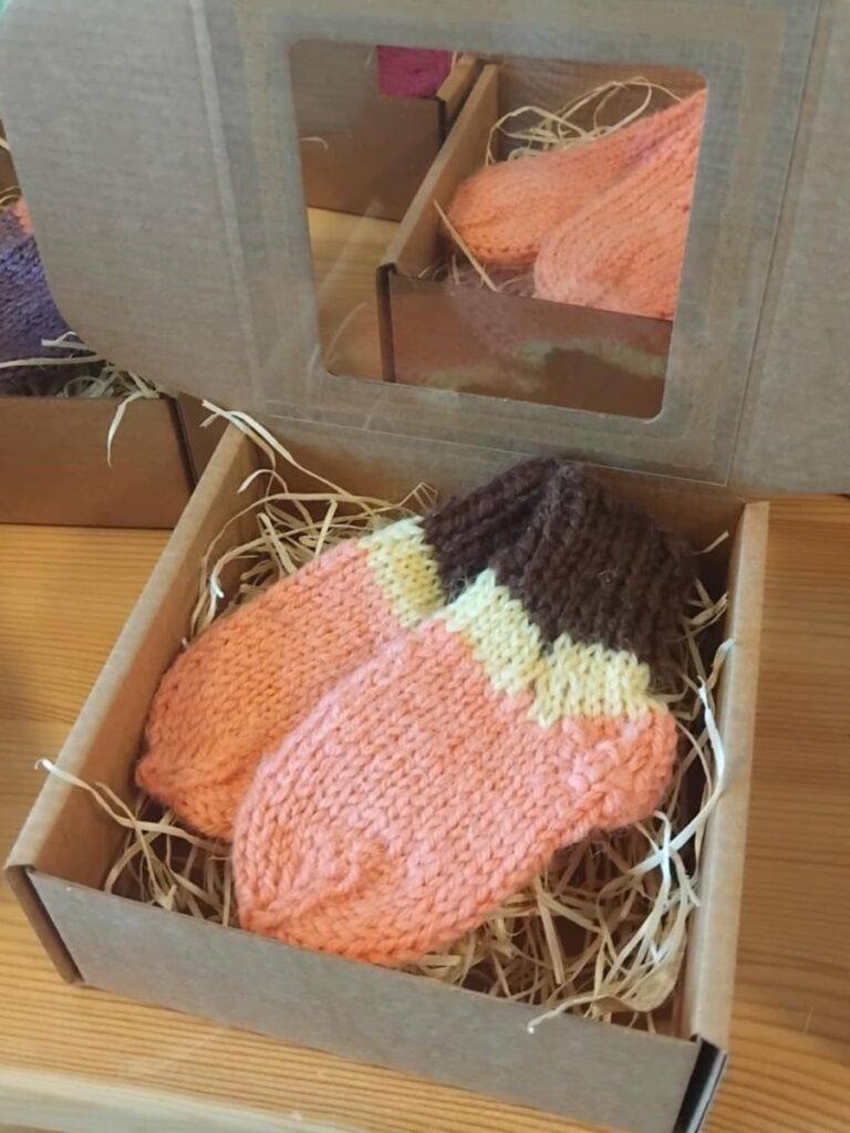 Kootud villased sokid karbis, mis on asetatud laua peale.