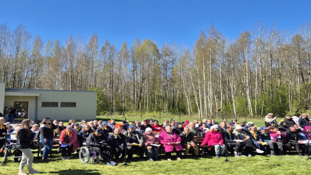 Inimesed istuvad pinkidel, taustal kevadine mets ja sinine taevas.