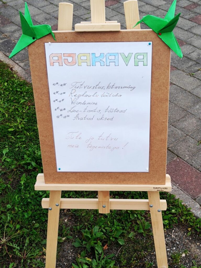 Ajakava silt elamuspäeva tegevustega, kaunistatud roheliste voltitud paberlindudega.