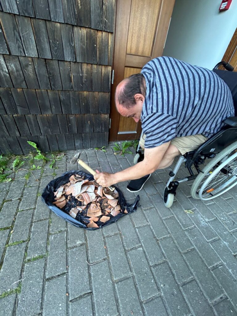 Ratastoolis mees purustab haamriga potikilde.