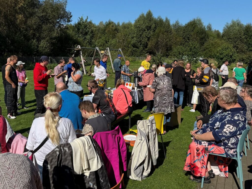 Rahvarohke kogunemine kodu õuealal, osalejad jälgivad tegevust ja vestlevad väikestes gruppides.