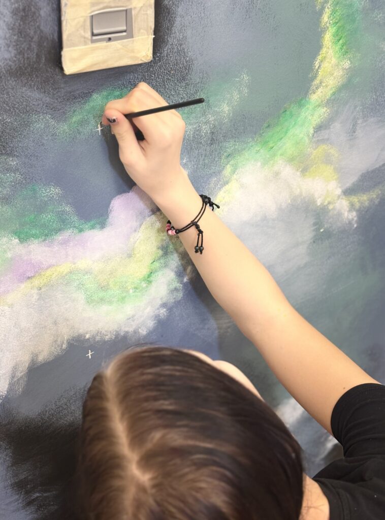 Noor maalib pintsliga galaktika seinamaalile väikest valget tähte.