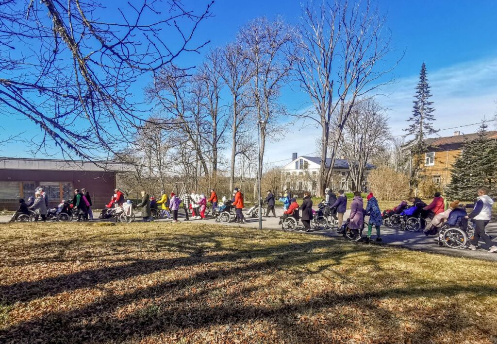 Südamenädala kooskõnnil liiguvad inimesed ühiselt kevadisel õuealal, osa osalejatest ratastoolis.